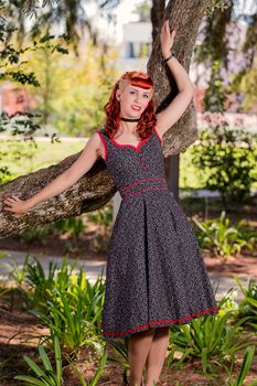 View of a young woman with a simple spring dress posing on the park.