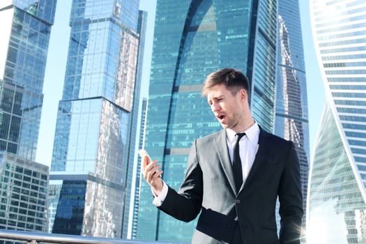 Businessman using smartphone on skyscraper background