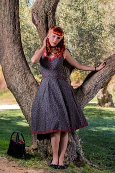 View of a young woman with a simple spring dress posing on the park.