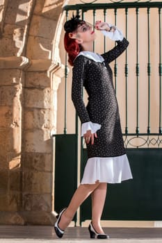 Close up view of a young redhead girl on a retro vintage dress on the urban city.