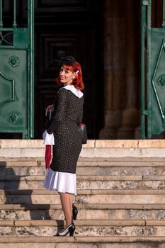 Close up view of a young redhead girl on a retro vintage dress on the urban city.