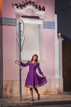 Close up view of a young redhead girl on a retro vintage dress on the urban city.