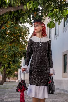 Close up view of a young redhead girl on a retro vintage dress on the urban city.