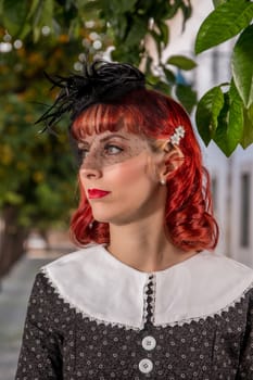 Close up view of a young redhead girl on a retro vintage dress on the urban city.