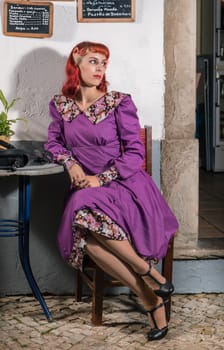 Close up view of a young redhead girl on a retro vintage dress on the urban city.