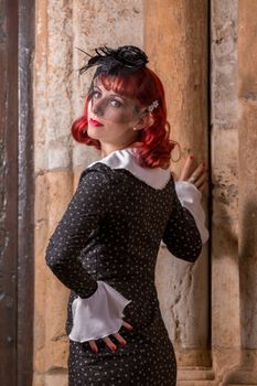 Close up view of a young redhead girl on a retro vintage dress on the urban city.