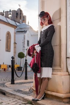 Close up view of a young redhead girl on a retro vintage dress on the urban city.