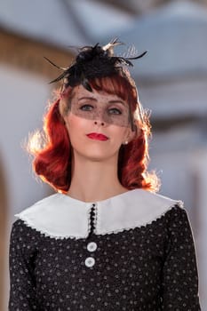 Close up view of a young redhead girl on a retro vintage dress on the urban city.