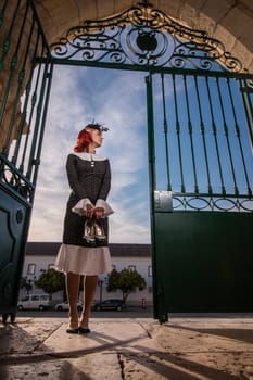 Close up view of a young redhead girl on a retro vintage dress on the urban city.