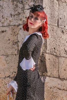 Close up view of a young redhead girl on a retro vintage dress on the urban city.