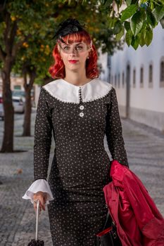 Close up view of a young redhead girl on a retro vintage dress on the urban city.