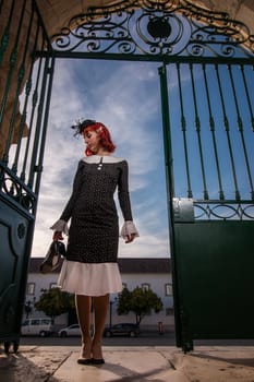 Close up view of a young redhead girl on a retro vintage dress on the urban city.