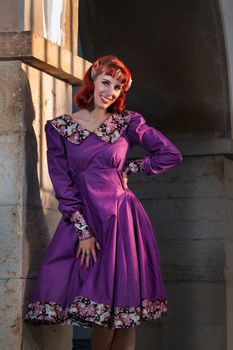 Close up view of a young redhead girl on a retro vintage dress on the urban city.