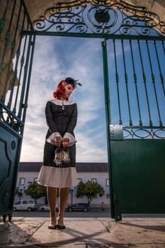 Close up view of a young redhead girl on a retro vintage dress on the urban city.