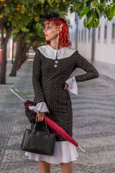 Close up view of a young redhead girl on a retro vintage dress on the urban city.