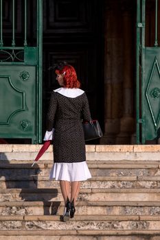 Close up view of a young redhead girl on a retro vintage dress on the urban city.