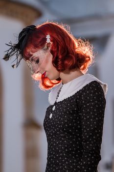 Close up view of a young redhead girl on a retro vintage dress on the urban city.