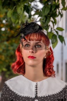 Close up view of a young redhead girl on a retro vintage dress on the urban city.