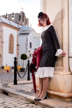 Close up view of a young redhead girl on a retro vintage dress on the urban city.