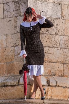 Close up view of a young redhead girl on a retro vintage dress on the urban city.