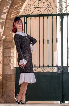 Close up view of a young redhead girl on a retro vintage dress on the urban city.