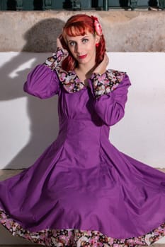 Close up view of a young redhead girl on a retro vintage dress on the urban city.