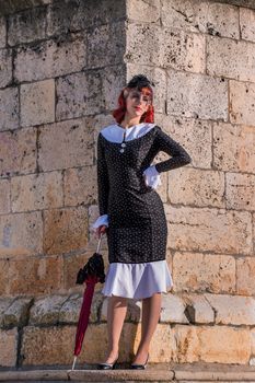 Close up view of a young redhead girl on a retro vintage dress on the urban city.