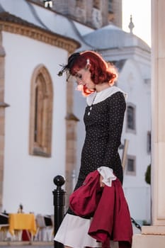 Close up view of a young redhead girl on a retro vintage dress on the urban city.