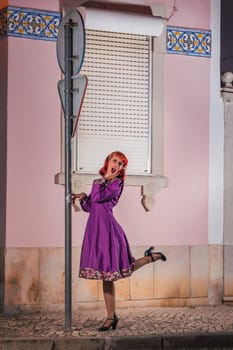 Close up view of a young redhead girl on a retro vintage dress on the urban city.