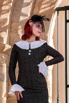 Close up view of a young redhead girl on a retro vintage dress on the urban city.