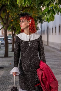 Close up view of a young redhead girl on a retro vintage dress on the urban city.