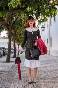 Close up view of a young redhead girl on a retro vintage dress on the urban city.