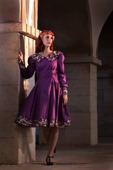 Close up view of a young redhead girl on a retro vintage dress on the urban city.