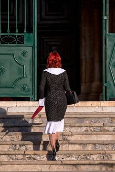 Close up view of a young redhead girl on a retro vintage dress on the urban city.