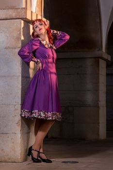 Close up view of a young redhead girl on a retro vintage dress on the urban city.