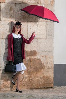 Close up view of a young redhead girl on a retro vintage dress on the urban city.