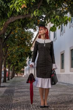 Close up view of a young redhead girl on a retro vintage dress on the urban city.