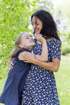 Embracing mother and daughter in summer on green background