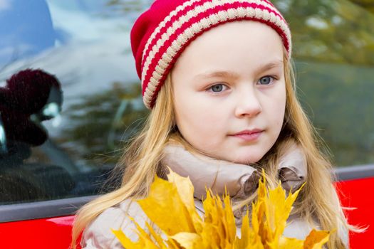 Portrait of cute smiling girl in red hat in autumn