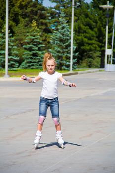 Learning girl on roller skates in summer