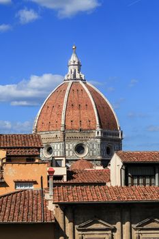 Close up top view of Florence houses with orange roofs and with a big dome, on cloudy blue sky background.