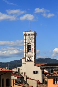 Close up top view of Florence houses with orange roofs and with a big belfry tower, on cloudy blue sky background.