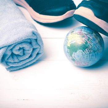 running shoes,towel and earth ball on white wood table concept world healthy vintage style