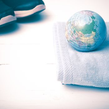 running shoes,towel and earth ball on white wood table concept world healthy vintage style