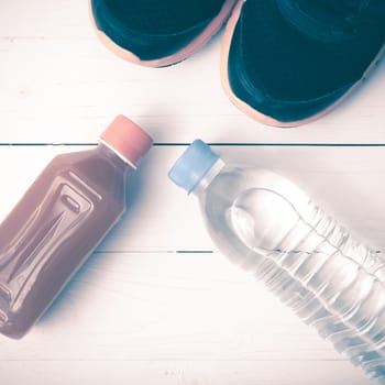 running shoes,drinking water and orange juice on white wood table vintage tone color style