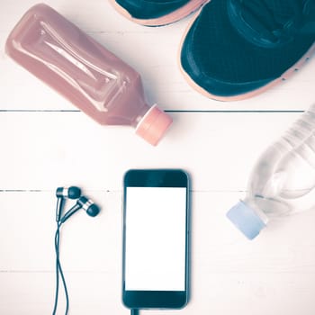 running shoes,orange juice,drinking water and phone on white wood background vintage tone color style