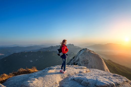 Woman stands on the peak of stone in Bukhansan national park,Seoul in South Korea and watching to Sunrise. Beautiful moment the miracle of nature.