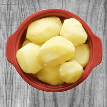 Potatoes in a ceramic pot on a background of old gray boards.
