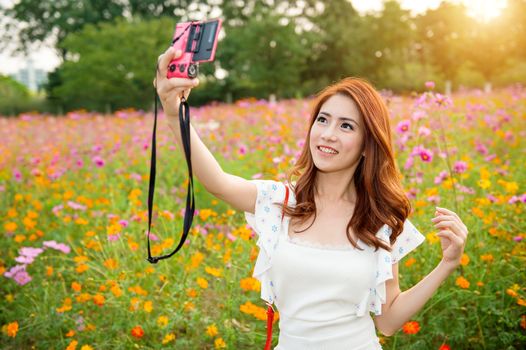 woman taking photos at a cosmos flowers.