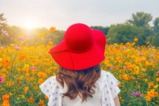 Woman wearing a red hat in a field of flowers.